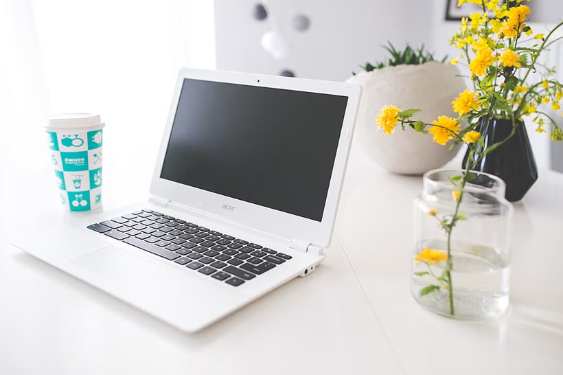A laptop and notebook open on a study desk with a coffee